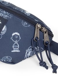 Pochette en tissu marine avec des impressions de personnages de dessin animé blancs, dotée de fermetures éclair et de cordons en argent, de forme rectangulaire et avec une surface texturée.