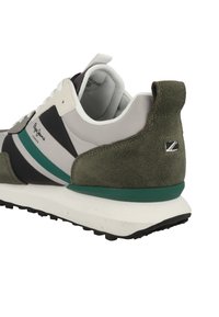 Gröna mocka- och syntetsneakers med vita och svarta accenter, med en texturerad sula och varumärke på sidan och baksidan.