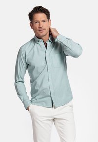 Lichtblauw overhemd met knopen en een borstzak, lange mouwen en een comfortabele pasvorm, gecombineerd met off-white broeken; gladde stoffen textuur.