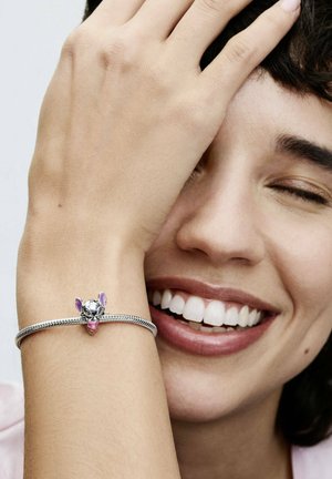 Ein silbernes Armband hat einen Anhänger in Form eines Tierkopfes, akzentuiert mit rosafarbenen Ohren und einem glänzenden silbernen Finish.
