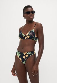 Zwart bloemenbikini met groene en oranje patronen. De top heeft een driehoekig ontwerp en de broekjes hebben een hoge taille.