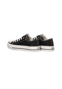 Zapatillas de lona negras con cordones blancos, suelas de goma y detalle de franjas negras. Presenta un logo y un acento de estrella en el talón.