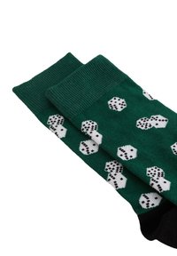 Calcetines verdes con punteras negras que presentan un patrón de dados blancos mostrando varios números.