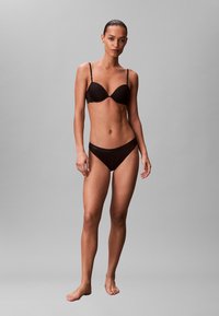 Czarny komplet bielizny składający się z formowanego biustonosza z cienkimi ramiączkami oraz dopasowanych, nisko osadzonych majtek, oba wykonane z teksturowanego materiału.