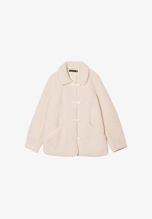 Veste en shearling crème avec un large col, des fermetures à boutons sur le devant et des poches latérales. Présente une texture douce et une coupe décontractée.