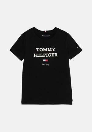 Sort t-shirt med korte ærmer og rund hals med "TOMMY HILFIGER", et lille rødt, hvidt og blåt flaglogo og "Est. 1985" trykt foran.