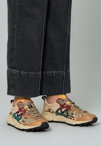 Flerfärgade sneakers med en blandning av beige, brunt och gröna material. Har leopardmönster, texturerade snörningar och en prickig sula.