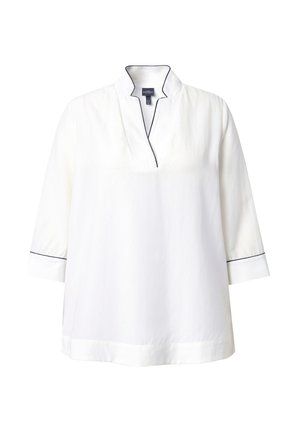 Tunique blanche avec col montant, manches trois-quarts et passepoil bleu marine le long du col et des poignets. Texture de tissu lisse.