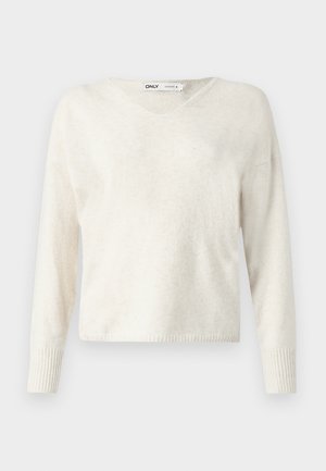 Pull crème en V en matériau doux, avec des manches longues et des poignets côtelés, au design légèrement cropped et décontracté.