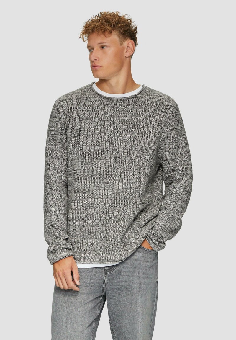Grijze gebreide trui met een textuurpatroon, ronde halslijn en lange mouwen, gecombineerd met lichtgrijze jeans.