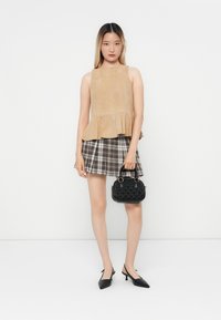 Beige mokkanahkapeplum-paita, ruskea- ja valkoisruudullinen mini-hame, musta teksturoitu käsilaukku ja mustat kärkitossut.