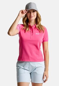 Roze polo shirt met korte mouwen en een knoopsluiting kraag, gecombineerd met lichtblauwe shorts. Een lichtgrijze pet maakt de outfit compleet.