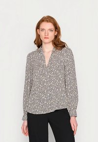 Chemise à manches longues boutonnée en imprimé léopard beige clair et noir, avec un col en V et une coupe décontractée, fabriquée dans un tissu lisse.