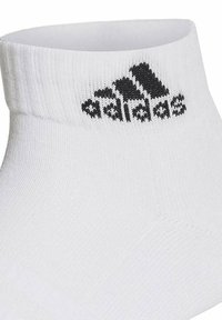 Calza sportiva bianca con polsino a coste, caratterizzata da un logo Adidas nero sulla caviglia. Realizzata in materiale traspirante con una vestibilità aderente.