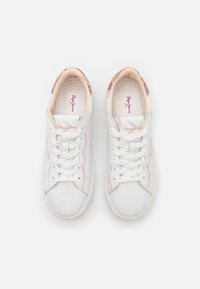 Valkoiset tennarit, joissa on sileä nahkaverhoilu, vaaleanpunaiset yksityiskohdat, teksturoitu sisus ja perinteinen nauhakiinnitys.