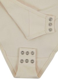 Bež bodysuit od mekog pamučnog materijala. Ima kopče na dugmad sa srebrnim metalnim detaljima i glatku teksturu. Vidljivi šavovi na ivicama.