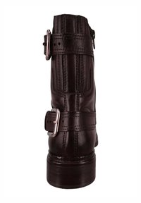 Bota de cuero marrón hasta el tobillo con costura vertical, dos correas ajustables con hebillas plateadas y puntera redondeada sobre un tacón resistente.