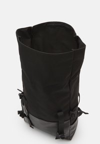 Rucsac negru tip roll-top, fabricat dintr-un material durabil, cu un fund din piele netedă. Include bretele ajustabile și o închidere cu fermoar.