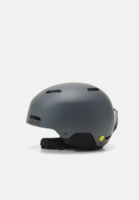 Casco Giro grigio con finitura opaca, slot di ventilazione integrati, cinturino regolabile e sistema di sicurezza MIPS in evidenza.