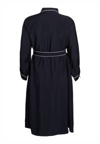 Crna midi haljina dugih rukava s bijelim detaljima na ovratniku, manžetama i remenu, prikazana s leđa.