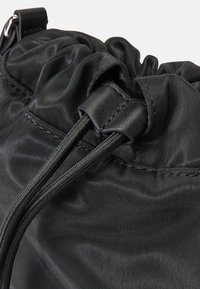 Borsa in nylon nera con coulisse, caratterizzata da una parte superiore arricciata con superficie testurizzata e chiusura sicura grazie ai blocchi cordonati rinforzati.