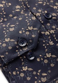 Marineblaues Hemd mit kleinem Blumenmuster in Gold- und Cremetönen, ausgestattet mit zwei dunklen Knöpfen und strukturiertem Stoff. Mit akzentuiertem Kragen- und Manschettendesign.