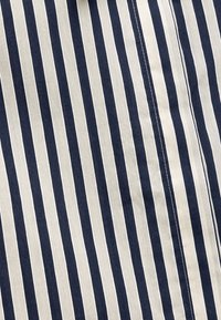 Tejido a rayas con franjas verticales alternadas en azul marino y crema, de textura suave, con costuras visibles a lo largo de las uniones.