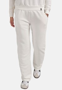 Witte sweatpants van een zachte katoenmix, met een trekkoord in de taille, zijzakken en een ontspannen pasvorm, gecombineerd met stijlvolle sneakers.