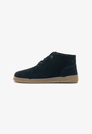 Stivaletti alla caviglia in suede blu navy con punta rotonda, design con lacci, suola in gomma beige a contrasto e branding laterale. Texture liscia con cuciture minime.