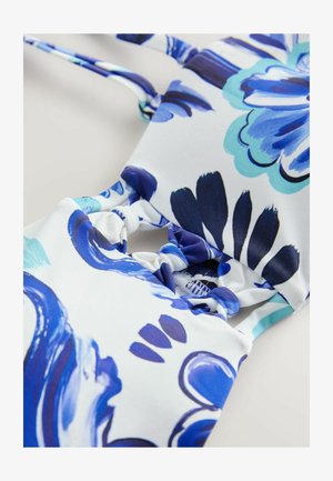 Balti maudymosi kostiumas su gėlėmis, puošniu mėlyna ir melsvai žalios abstrakčiomis raštas. Medžiaga lygi, su gumulėlių detalėmis ir reguliuojamomis petnešomis.