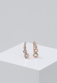 Pendientes de oro rosa con un diseño en cascada de cinco cristales circulares y transparentes de diferentes tamaños, sobre un fondo liso y neutro.