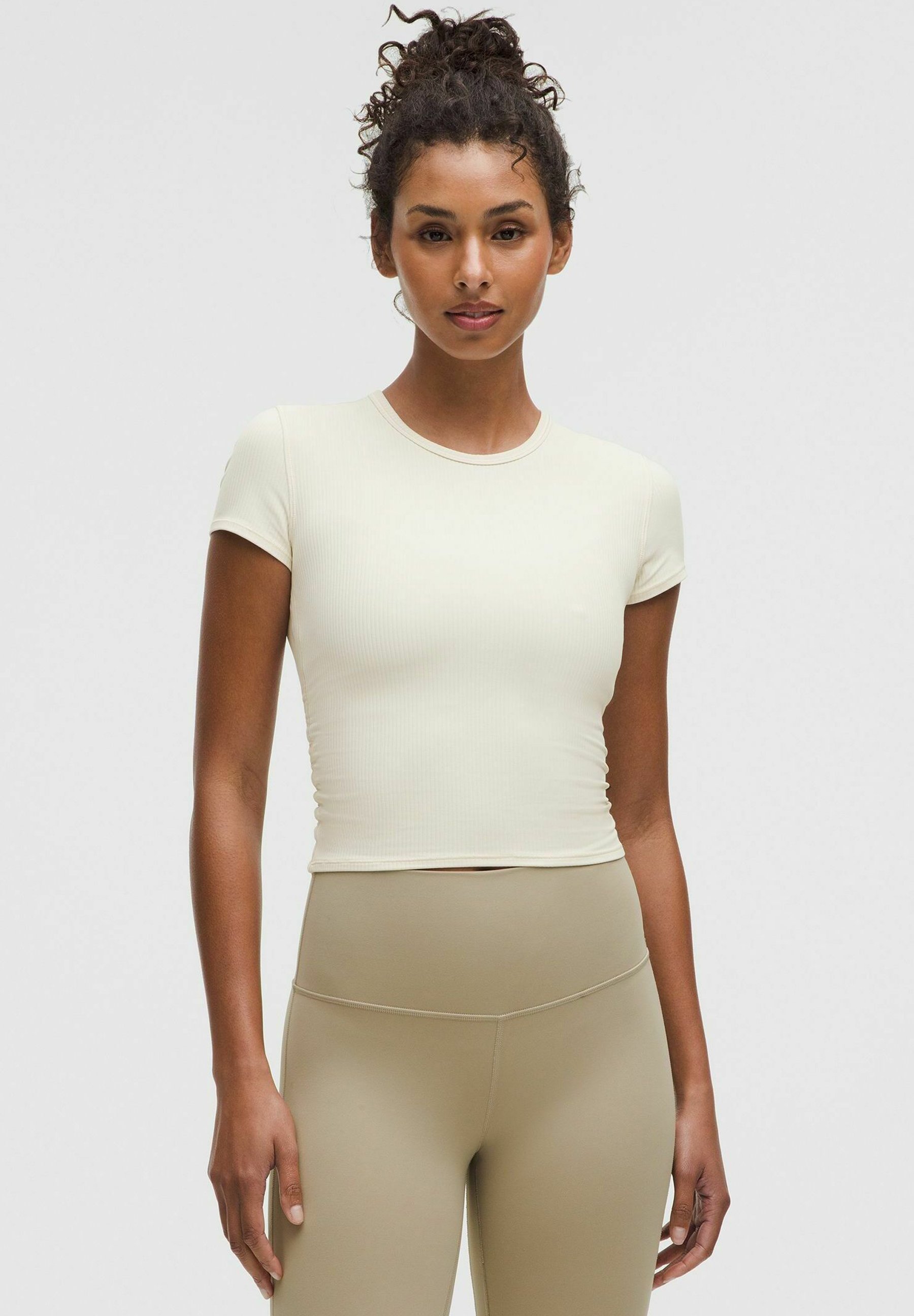 Svetlo bež rebrovan kratki top s kratkimi rokavi, prilegajoča se zasnova, okrogli izrez in gladka tekstura, ohišje z visoko pasom bež legicami.
