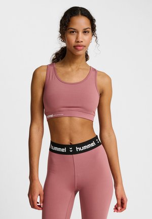 Roze sportbeha met een brede band met het "hummel"-logo, gecombineerd met bijpassende high-waisted leggings met een zwarte tailleband. Soepele textuur.
