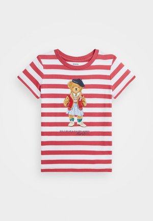 T-shirt à manches courtes rayé rouge et blanc avec un ours portant une veste, une jupe, un béret et des baskets imprimé au centre.