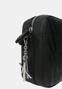 Borsa nera con texture, chiusura lampo e catena argentata con ciondolo. Presenta una finitura in pelle martellata e un design in rilievo sulla superficie.