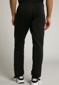 Pantaloni sportivi neri con vestibilità affusolata, realizzati in un tessuto liscio e leggero, dotati di tasche laterali e cintura elastica.