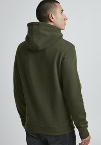 Olive green hooded sweatshirt made of cotton blend, featuring a relaxed fit, ribbed cuffs, and a solid texture with minimal stitching detail.