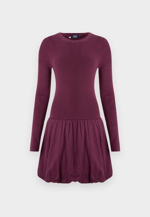 Paarse jurk met een geribbelde lijfje, lange mouwen en een geplooide rok. De stof oogt glad en heeft een lichte textuur.