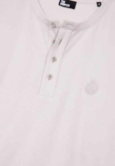 Helles beigefarbenes Henley-Shirt mit drei Knöpfen und dezentem besticktem Wappen auf der Brust, Etikett "The Kooples", Größe M.