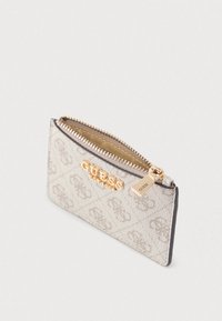 Bézs színű, cipzáros pénztárca aranyozott "GUESS" logóval, mintás textúrával és cipzárhúzó díszítéssel. Kompakt és téglalap alakú.