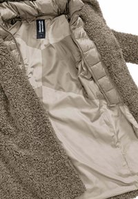 Bruine pluizige buitenstof met een pluche textuur en taupe gladde voering; heeft een ritsluiting en een hanglabel.