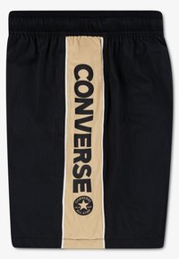 Shorts noirs avec une taille élastique. Ils comportent une bande beige verticale avec "CONVERSE" en lettres noires en gras et un logo en bas.