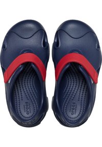 Scarpe di plastica blu navy con cinturini in gomma rossi, caratterizzate da una soletta testurizzata e fori per la ventilazione. Forma arrotondata con una finitura liscia.