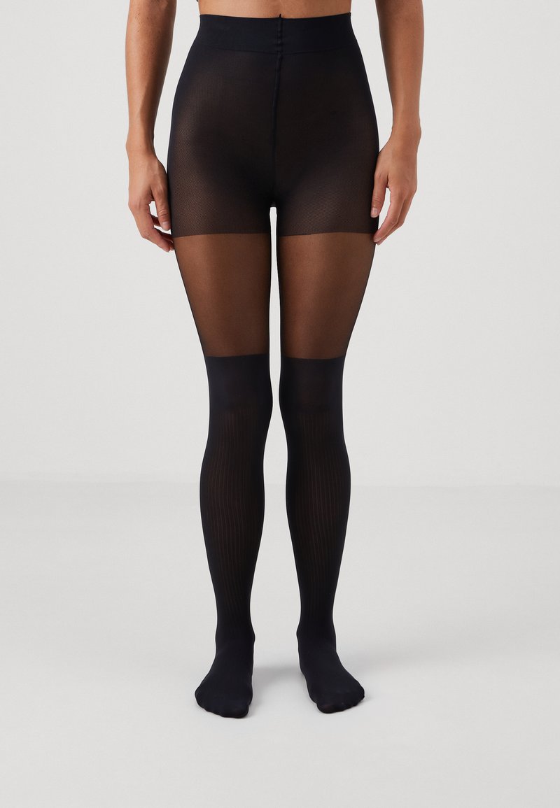Svarta genomskinliga nylonstrumpor med hög midja, med en strukturerad ovandel och en slät underbendel, som betonar en genomskinlig till midjan-design.