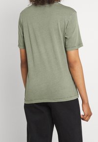 Olivgrön t-shirt med korta ärmar i en avslappnad passform, med rund halsringning och rena sömmar vid fållarna.