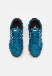 Modré syntetické sportovní boty s detailním síťovinovým materiálem, černými akcenty, žlutým logem a gumovou podrážkou. Disponují klasickým šněrovacím designem.
