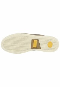 Suela de zapatilla marrón con patrón de agarre texturizado, goma de color crema, con un acento amarillo y detalle del logo. Diseño ligero y flexible.