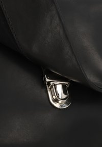 Black leather bag featuring a textured surface. The closure is a shiny silver clasp, highlighting contrasting materials and finishes.
