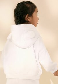 Felpa bianca con cappuccio a cui sono applicate orecchie rotonde, taglio morbido e maniche a coste. Tessuto morbido, adatta per un look casual.