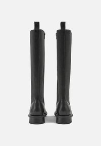 Botas de couro pretas até ao joelho com uma textura suave, apresentando um fecho zip na parte de trás e um salto de borracha empilhada para maior estabilidade.